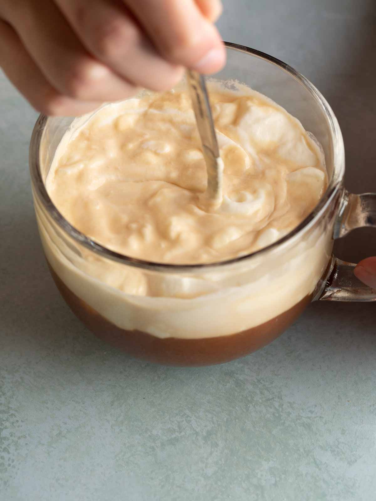 A glass of authentic Salt Coffee Vietnam (Cà Phê Muối) with a thick layer of salted foam on top of dark Robusta coffee beans by Local Beans Roastery.